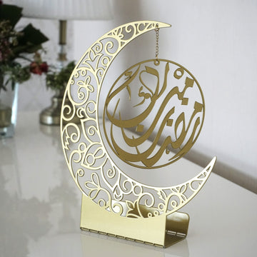 Altın renkli hilal ve içinde asılı Arapça Ramazan Kerim yazılı daire, metal masa ve raf dekoru