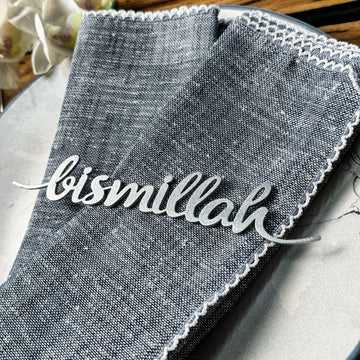 Gümüş Bismillah yazılı metal peçete süsü, mavi keten peçetenin üstünde yakın çekim