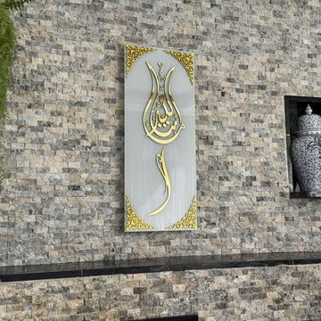 Beyaz cam üzerine altın akrilik hatlı lale formlu Maşallah hatlı temperli cam tablo, taş duvarda