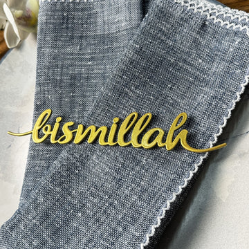 Altın Bismillah yazılı metal peçete süsünün mavi keten peçete üzerinde yakın görünümü
