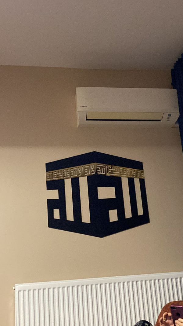 Klimanın altında duvarda lacivert Kâbe biçimli kufi Allah yazısı