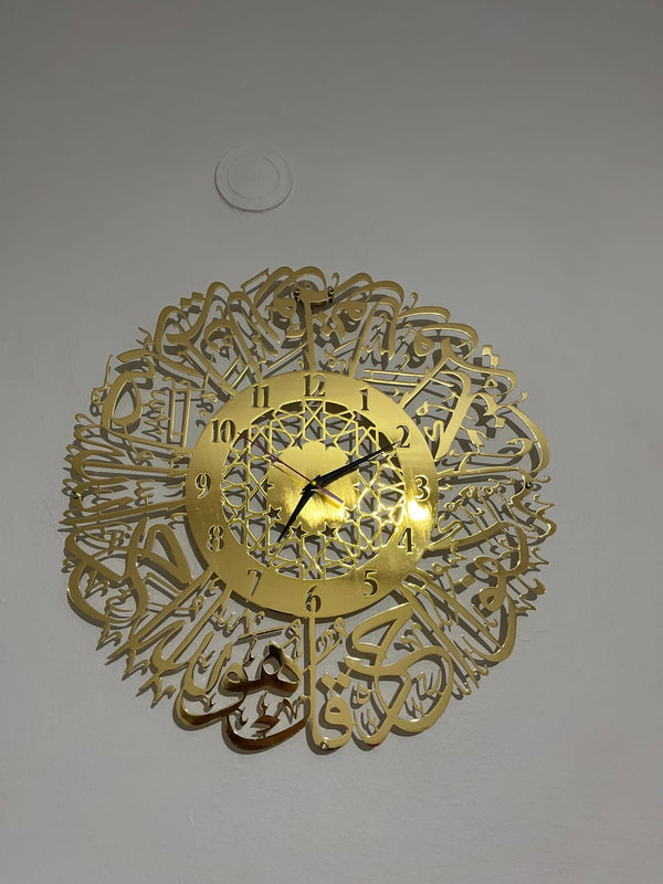 Duvarda altın renkli sure hattı çerçeveli duvar saati