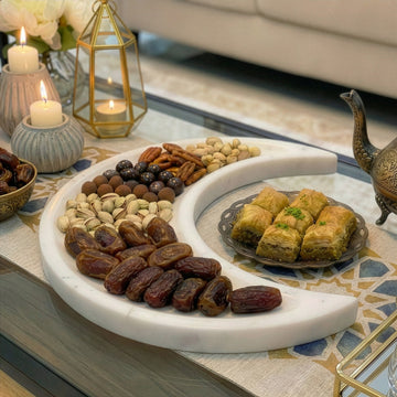 Hilal mermer servis tabağının yakın görünümü, hurma, kuruyemiş ve baklava dolu
