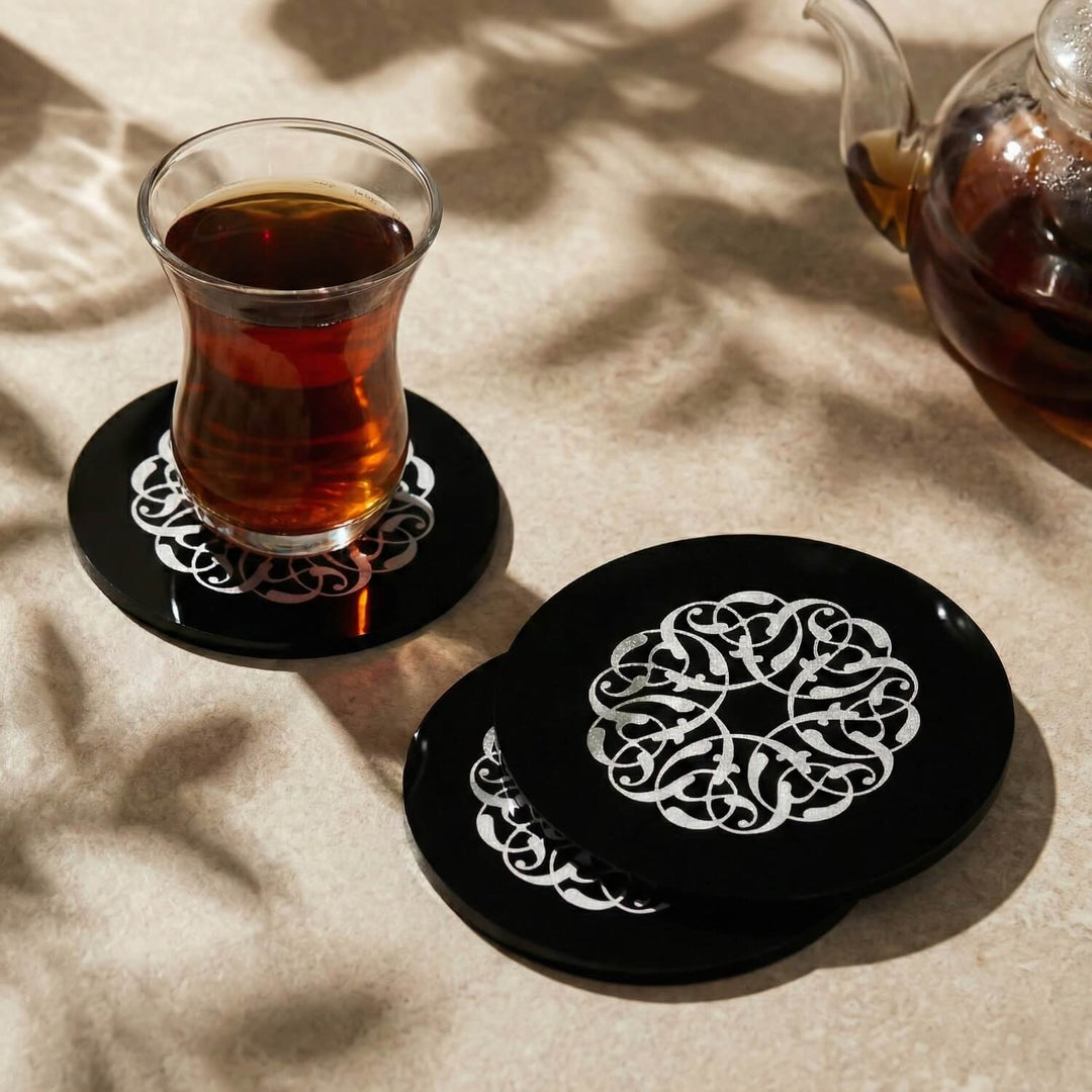 Rumi Desen siyah akrilik bardak altlığı, gümüş desenli yüzey, çay bardağıyla birlikte