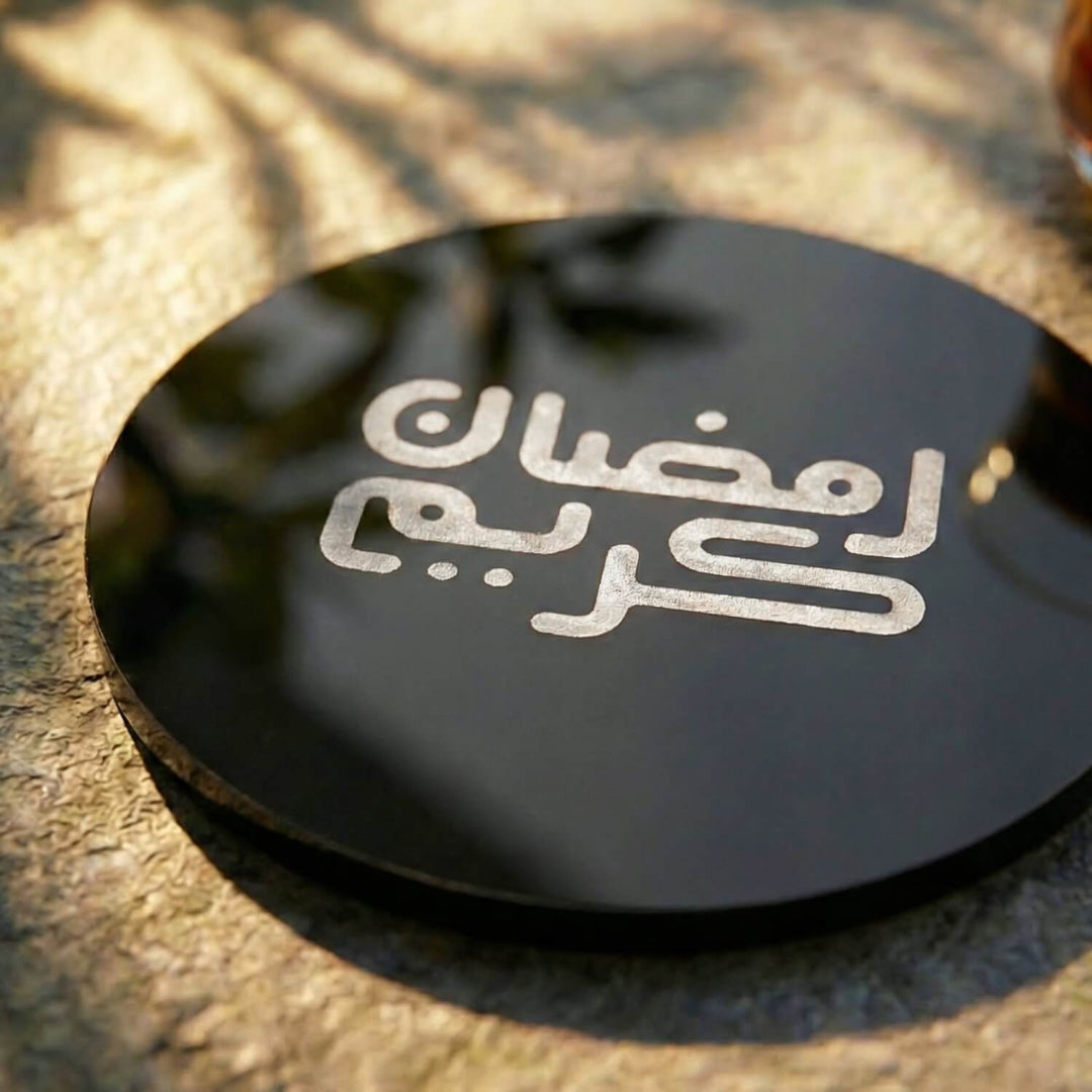 Yuvarlak Kufi Hat Ramazan Kerim yazılı siyah akrilik bardak altlığının açılı yakın çekimi