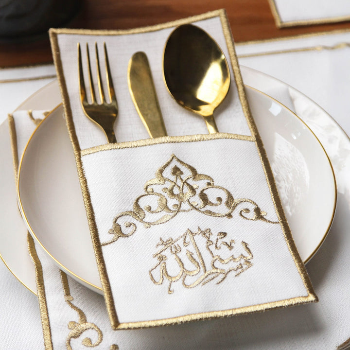 islamicwallart beyaz kumas uzerine altin rengi nakis islemeli servis cebi icerisinde altin sarisi catal, bicak ve kasik takimi bulunmaktadir