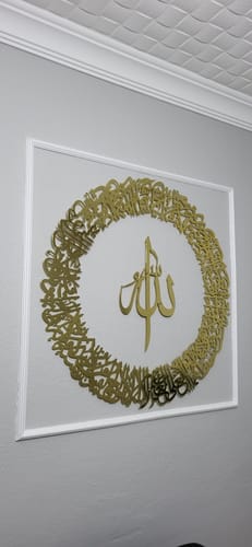 Beyaz çerçevede altın renkli yuvarlak ayet hattı ve ortada Allah lafzı