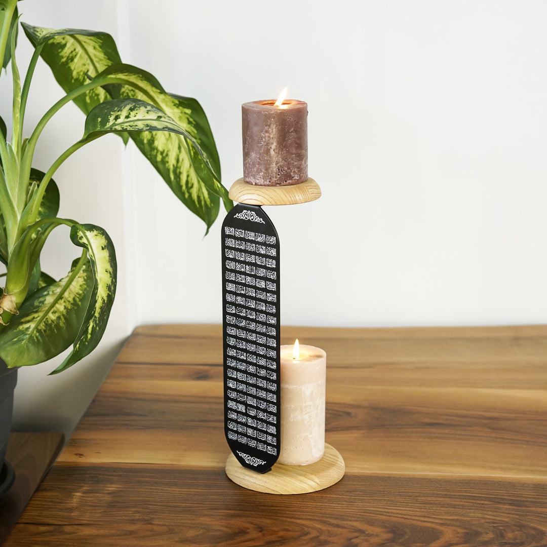 altta ve ustte mum ahsap mum standi olan siyah metal mumluk uzerinde arapca dikey sekilde yazan esmaul husna ile dikkat cekiyor islamicwallarttr