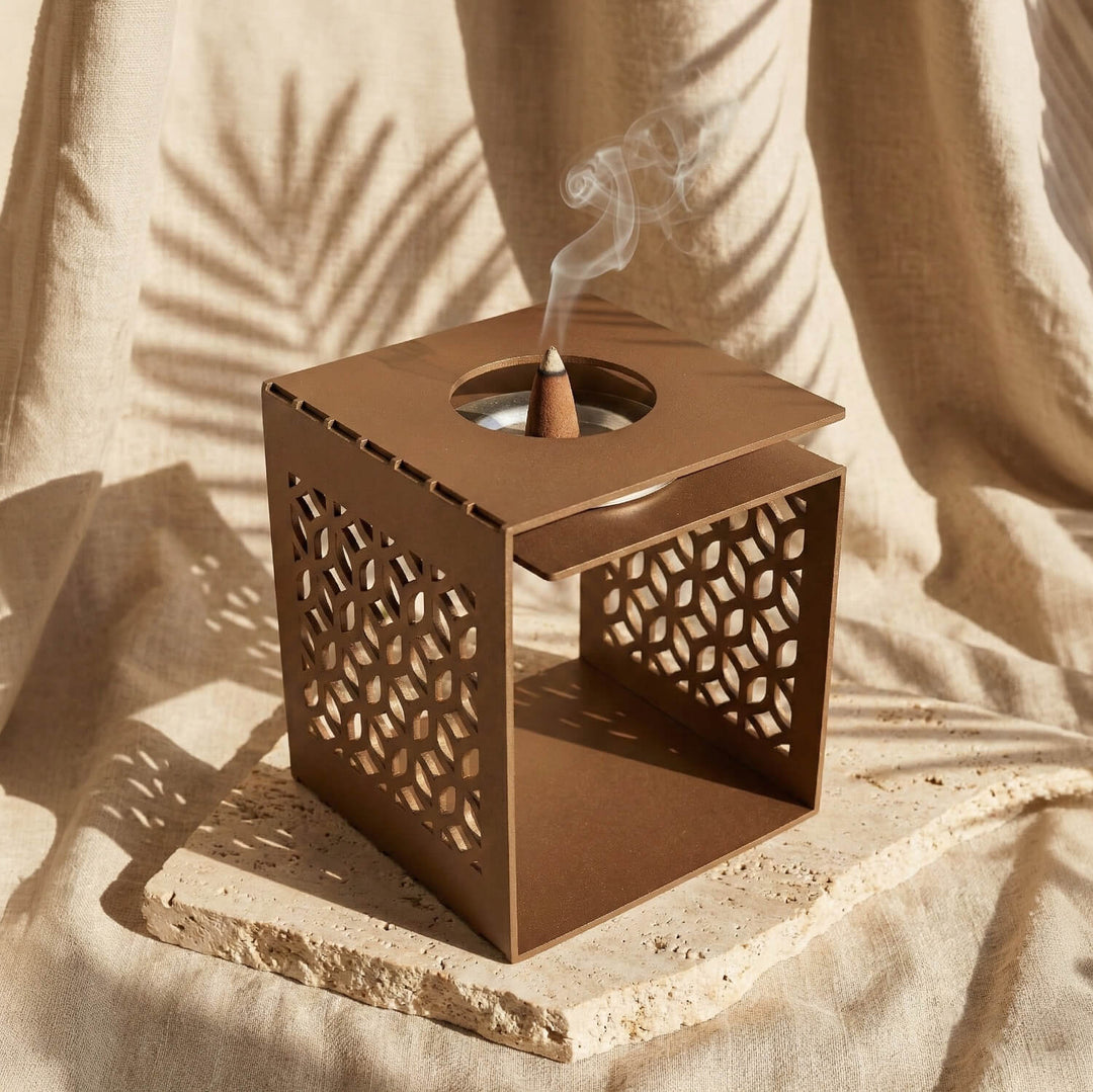 Bakır renkli geometrik motifli metal buhurdanlık, üst plaka açıklığından yükselen tütsü dumanı