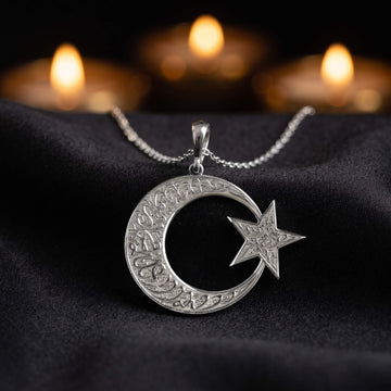 Gümüş renkli Kelime-i Tevhid ay yıldız kolye, arkada yanan mumlarla siyah kumaş üzerinde