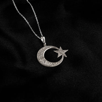 925 ayar gümüş ay yıldız kolye, sol üstten inen ince zincirle siyah kumaş üzerinde küçük kolye ucu
