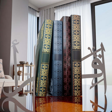 Gümüş İkra yazılı metal kitap tutucu, camlı sehpada kitapların iki yanında