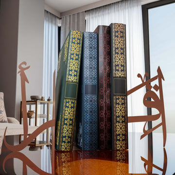 Bakır İkra yazılı metal kitap tutucu, camlı sehpada kitapların iki yanında