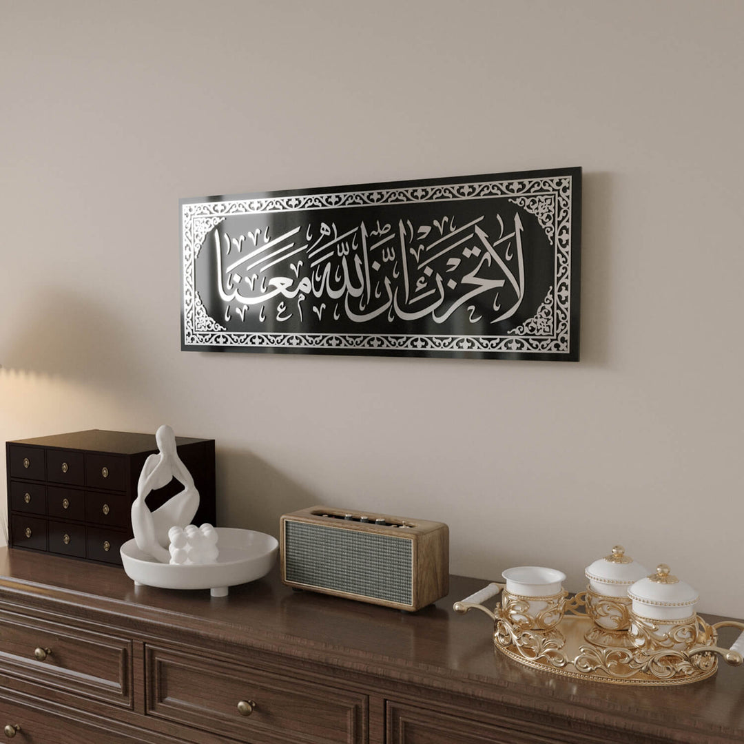 Minimalist ve klasik iç mekan tasarımlarına uyum sağlayan La Tahzen İnnallahe Meana Cam Tablo - Tevbe Suresi 40. Ayet.
