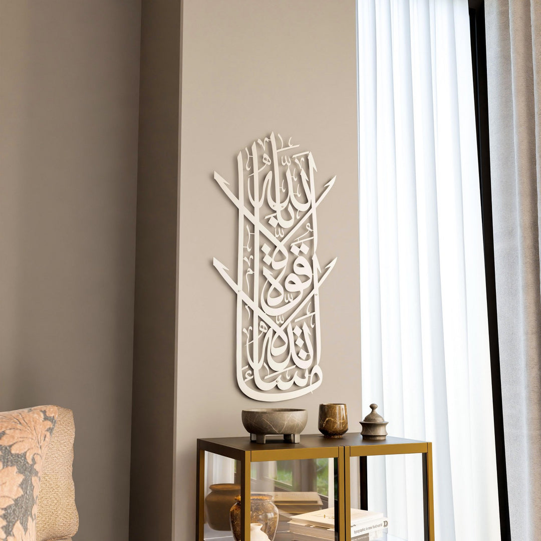 Gümüş Maşallah Lâ Havle ve Lâ Kuvvete dikey hatlı metal tablo, koltuk ve yan sehpa yanındaki duvarda