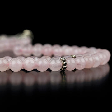 Pembe kuvars 99'luk tesbih, 6 mm habbeler ve metal ayırıcı, siyah zeminde yandan yakın çekim