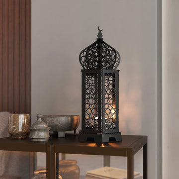 Siyah Ramazan kandili metal dekor, içindeki mum ışığıyla yan masanın üzerinde