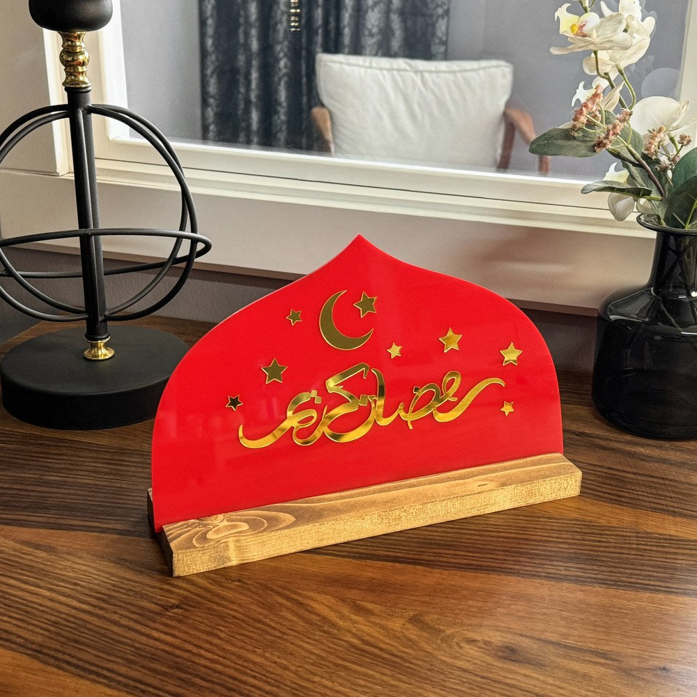 Kırmızı pleksi üzerinde altın akrilik Arapça Ramazan Kerim yazılı, ahşap standlı masa ve raf dekoru