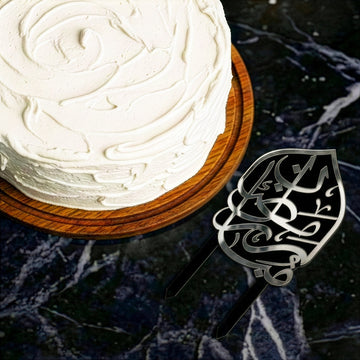 Siyah üzeri gümüş Ramazan Mübarek pasta süsü, mermer zeminde pastanın yanında üstten görünüm