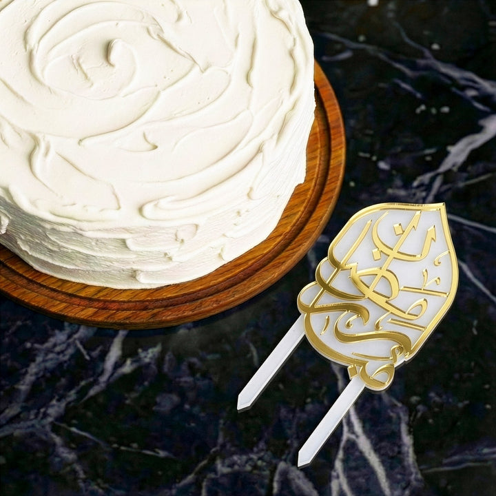 beyaz kremali pastanin ustten gorunumu ve yaninda yerlestirilmis altin renkli arapca ramazan kerim yazili buzlu beyaz akrilik kek topper islamicwallarttr