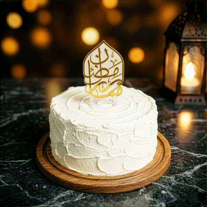 beyaz kremayla kapli yuvarlak pastanin uzerinde buzlu beyaz ayakli altin renkli arapca ramazan kerim yazili akrilik kek topper islamicwallarttr