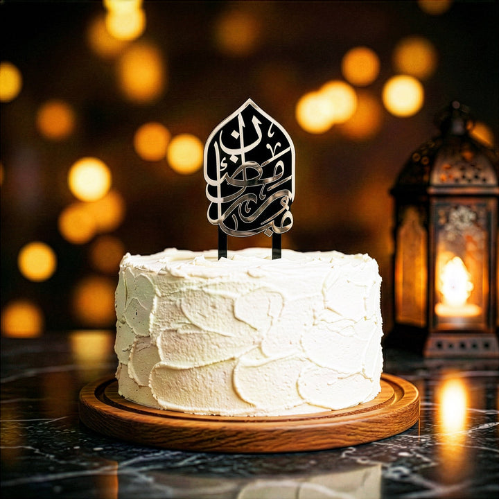 beyaz kremayla kapli yuvarlak pastanin uzerinde gumus renkli arapca ramazan kerim yazili akrilik kek topper arka planda los isiklar ve dekoratif fener ile sik ramazan sunumu islamicwallarttr
