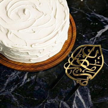 Siyah üzeri altın Ramazan Mübarek pasta süsü, mermer zeminde pastanın yanında üstten görünüm