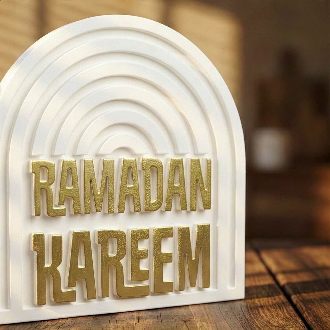 Altın yaldızlı Ramazan Kerim kabartma yazısının yakın çekimi, kemerli beyaz taş dekor