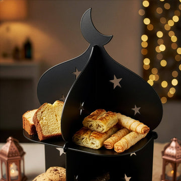 Siyah metal minare standının hilal ve yıldız oymalı üst katı, börek ve kek dilimiyle çok yakın çekim