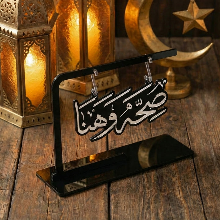 Ramazan sofralari icin siyah stantli, beyaz Arapca kaligrafiyle sihhat ve afiyet yazili modern akrilik masa aksesuari islamicwallarttr