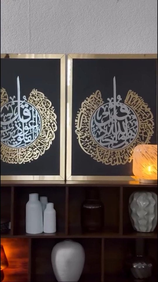 Siyah fonlu iki yuvarlak ayet hattı tablosu, altın ve gümüş renkli, raf üstünde