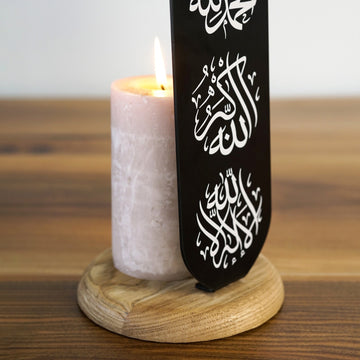Siyah mumluğun Allahu Ekber ve La İlahe İllallah yazıları, yanında yanan krem mum yakın çekim