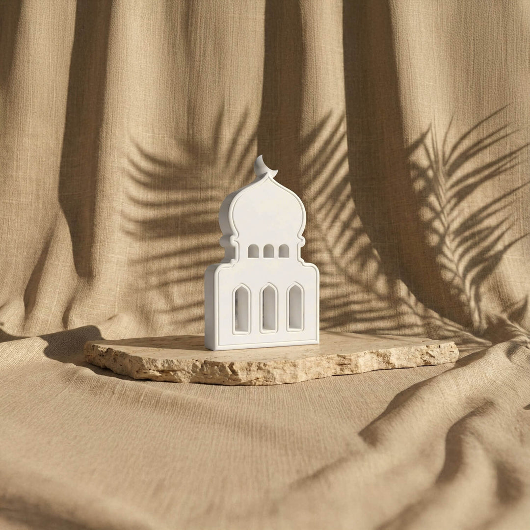 Taş cami biblo, üç kemerli pencereleri ve hilalli kubbesiyle bej fonda karşıdan görünüm
