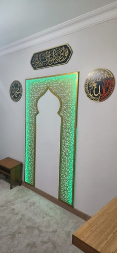 Yeşil ışıklı mihrap biçimli pano, çevresinde hat levhaları, namaz köşesi