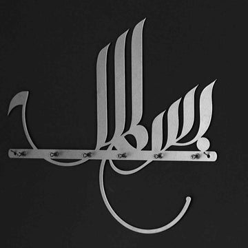 Gümüş Besmele hat yazılı metal anahtarlık, koyu duvarda önden görünüm