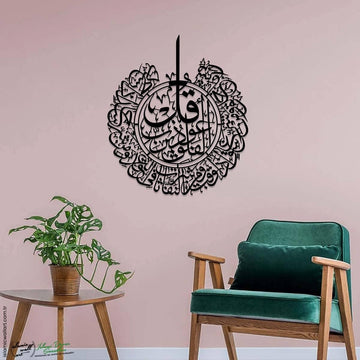 Siyah Felak Suresi dairesel metal tablo, pembe duvarda yeşil koltuğun üstünde