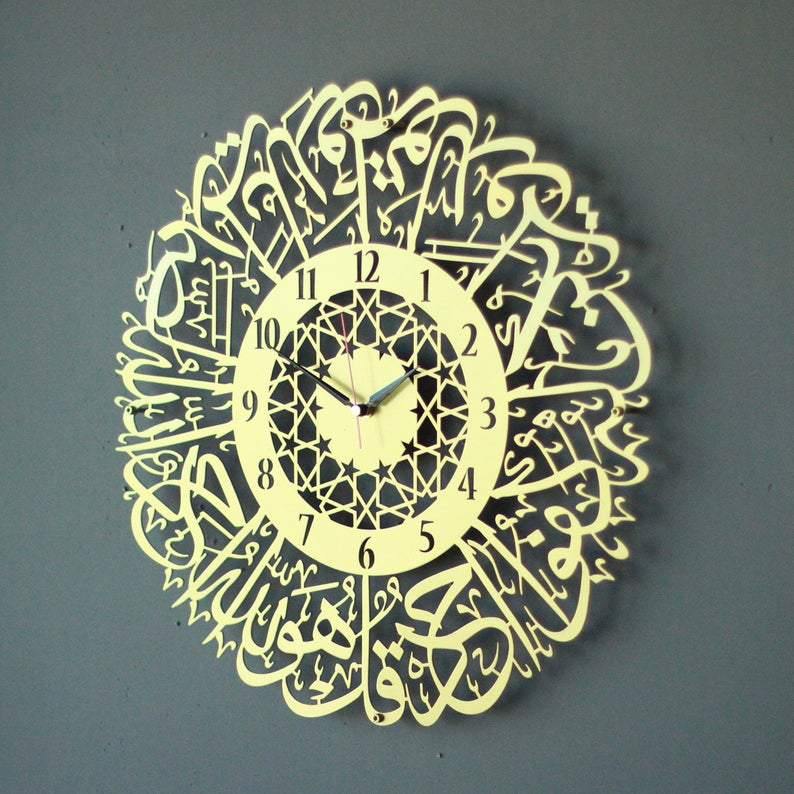 Altın İhlas Suresi Latin rakamlı desenli metal duvar saati, yıldız desenli iç halkalı, gri duvarda