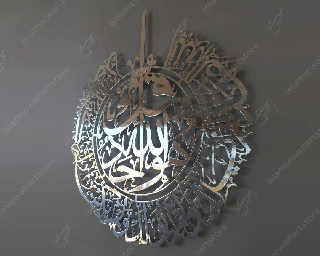 Parlak gümüş İhlas Suresi metal tablo, sol alttan açılı görünüm, yüzeyde ışık yansıması