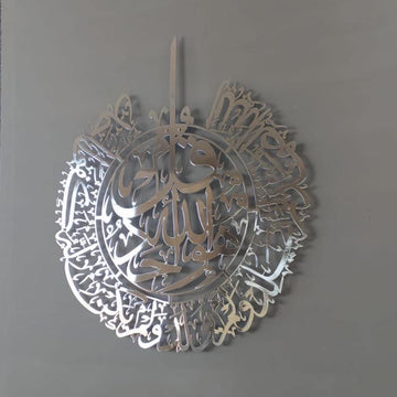Gümüş İhlas Suresi parlak metal tablo, gri duvarda hafif yandan açılı görünüm
