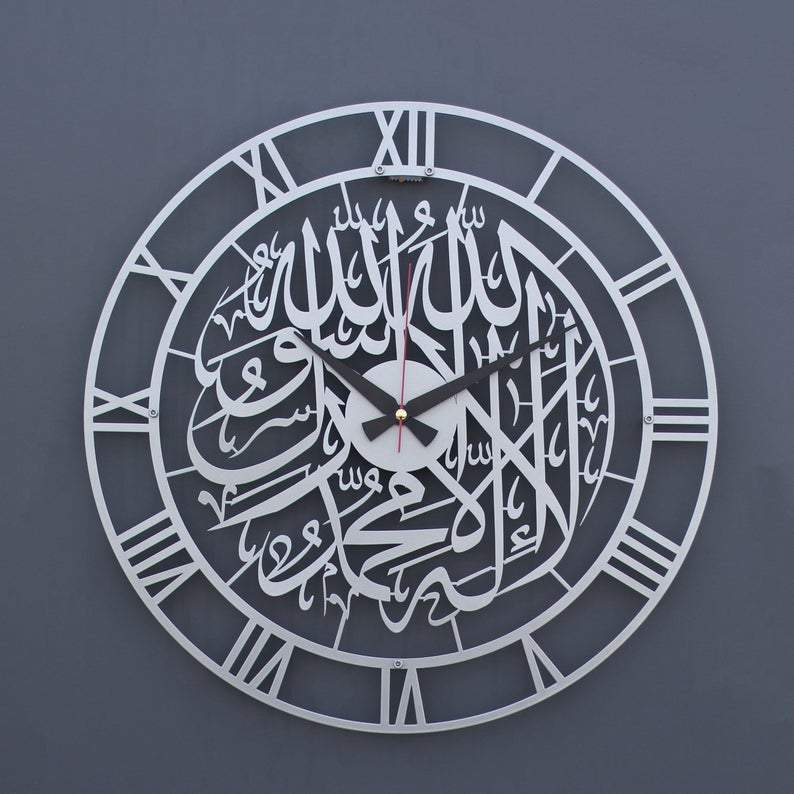 Gümüş Romen rakamlı Kelime-i Tevhid metal duvar saati, gri duvarda ön görünüm