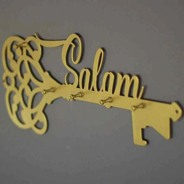 Altın renk Salam yazılı anahtar şeklinde metal anahtarlık, gri duvarda yandan açılı görünüm
